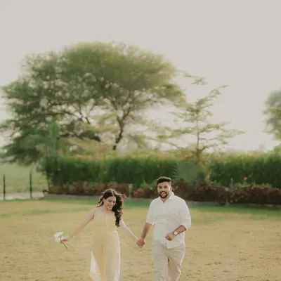 A happy couple runs hand-in-hand through a green field. This candid engagement photo is full of movement and genuine smiles, capturing the pure fun of being together.
