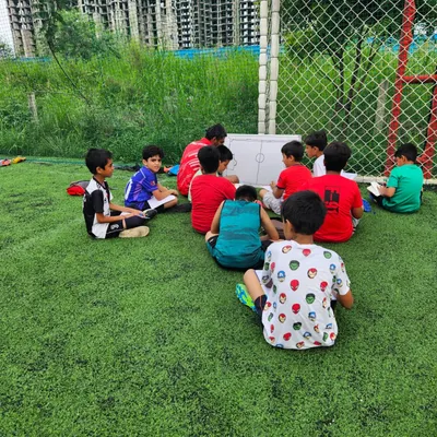 Learning the game from a different perspective. A coach uses the whiteboard to explain formations and player roles to our young athletes, building their football IQ.