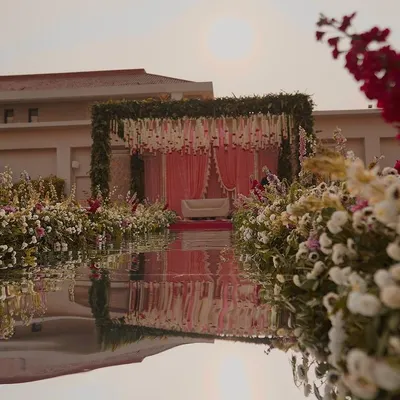 A breathtaking view of a wedding mandap set against the water. We created a floral paradise with a lush aisle and a canopy of greenery, perfectly reflected to create a mirror image of the stunning setup.