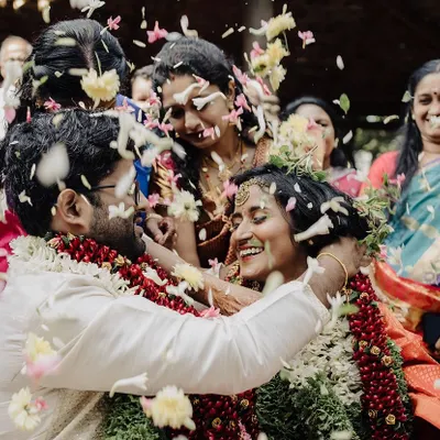 A perfect shower of petals and blessings. This candid shot captures the peak of celebration during a South Indian wedding ritual, freezing a moment of pure happiness and family participation.