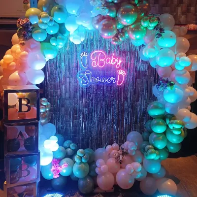 A closer look at this modern baby shower backdrop. The combination of the 'Baby Shower' neon sign against the shimmer curtain and multi-colored balloons creates a fantastic effect in photos.