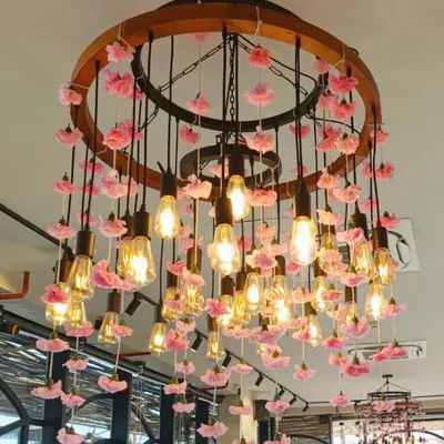Lighting is a key element of our designs. This custom chandelier, featuring exposed Edison bulbs adorned with delicate pink flowers, created a warm and romantic glow, serving as a stunning centerpiece for the entire room.