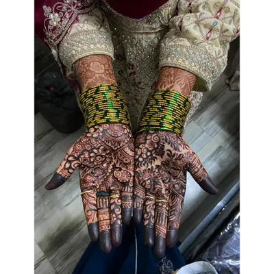 A complete bridal look with full palm and finger coverage. The design features a dense pattern of florals and traditional motifs, with the fingertips dipped for that classic deep color.