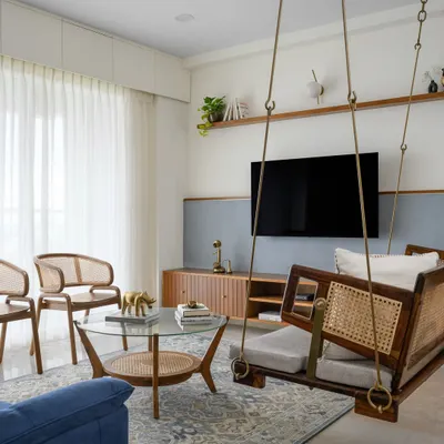 The living space in our 'Malhar' project is centered around a traditional Indian swing. The sleek veneered TV unit and textured half-wall create a contemporary classical feel, completed by rattan chairs.