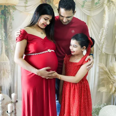 Including the whole family is so important. This beautiful family portrait shows the older sister-to-be gently touching her mom's baby bump in our cozy studio.