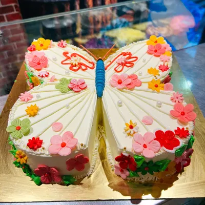 A stunning butterfly-shaped cake decorated with a garden of colorful buttercream flowers. This unique sculpted cake is perfect for a spring or garden-themed party.