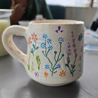 A beautifully hand-painted mug featuring delicate wildflowers. This shows how you can turn a simple clay mug into a personal piece of art to use every day.