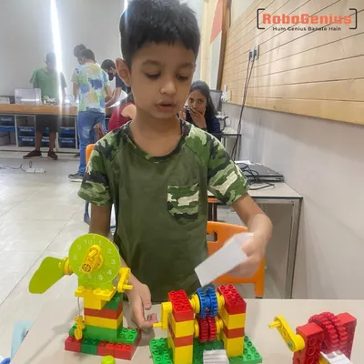 A first-grade student from our Tinkering course demonstrates his creation. Using LEGO gears and parts, he has built a working model of a fan, learning about gear ratios and mechanics in a tangible, engaging way.
