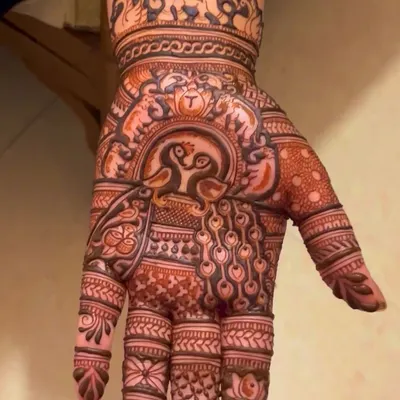 This design is filled with traditional Rajasthani motifs. It features loving peacocks in the center, surrounded by elephant figures at the wrist and detailed finger patterns.