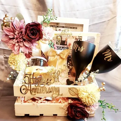 Celebrating a 25th anniversary with this grand hamper. It includes "Mr" and "Mrs" glasses, a vintage photo frame, and other personalized items, all beautifully arranged in a wooden crate.