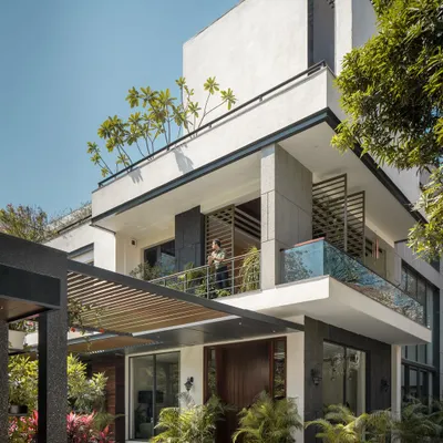 The exterior of Twin Villa showcases a modern aesthetic with clean lines, cantilevered balconies, and large glass openings. The structure is designed to interact with its lush surroundings, with greenery integrated at every level.