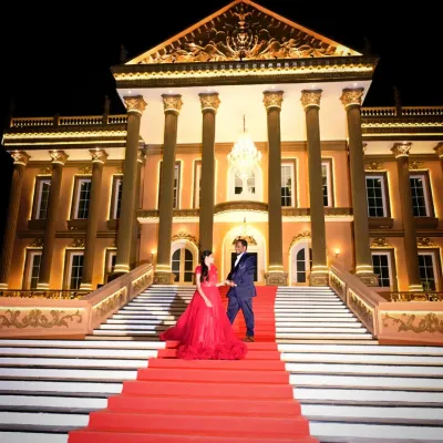 Create a grand, cinematic pre-wedding photo with our red ball gown. This couple's shot on a majestic staircase looks like a scene from a movie.