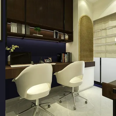 This home office is designed for two, with a long, shared desk against a deep blue wall. Overhead shelving with integrated lighting provides ample storage and a warm ambiance, while the modern white chairs offer comfortable seating.