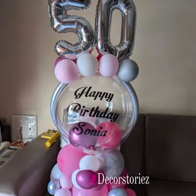 A personalized balloon bouquet perfect for a milestone 50th birthday. This custom arrangement features a large clear balloon with a 'Happy Birthday' message, foil numbers, and a mix of pink, white, and silver balloons.