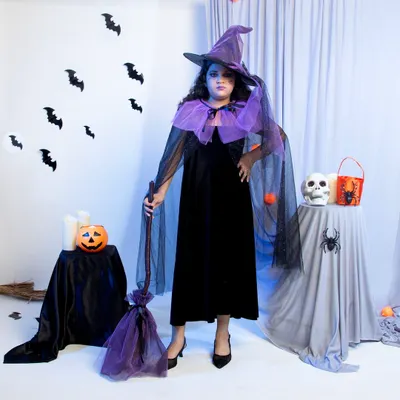 A full-length shot of a child's witch costume, captured against a custom-built Halloween set in the studio. This type of image is perfect for a main product listing on Amazon or Flipkart, as it shows the entire costume, accessories, and overall theme at a glance.