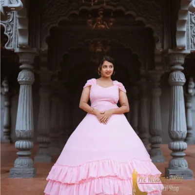 This light pink ball gown features a full skirt with tiered ruffles, creating a soft, romantic, and princess-like silhouette. It's perfect for grand, architectural settings.