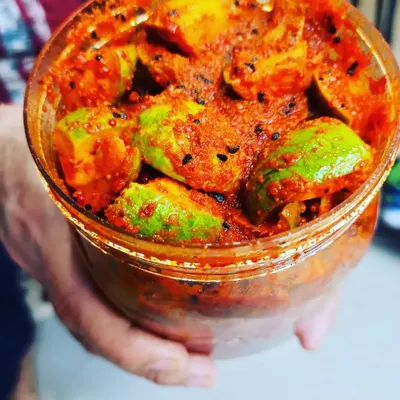 A handful of my homemade mango pickle. This close-up shows the rich red masala and black kalonji seeds coating every piece of raw mango.