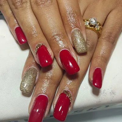 A full view of these stunning bridal nails. The combination of deep red gel polish, gold glitter accent nails, and carefully placed stones at the cuticle creates a look of pure opulence.