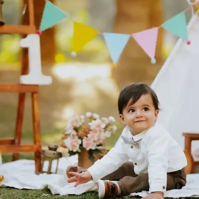A perfect outdoor picnic setup for a first birthday. This little boy looks so dapper in his bow tie against the colorful bunting and teepee.
