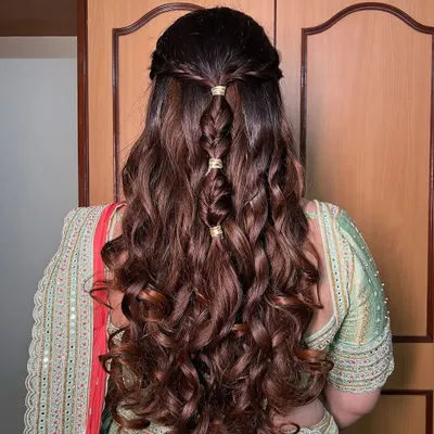 A beautiful braided hairstyle with soft curls, perfect for a traditional or modern look. The small gold accessories add a touch of elegance.