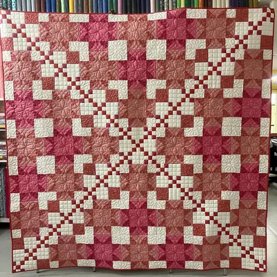 A stunning combination of a Star and Irish Chain pattern, this quilt features intricate piecing in shades of pink and rose. Our quilting adds another layer of texture.
