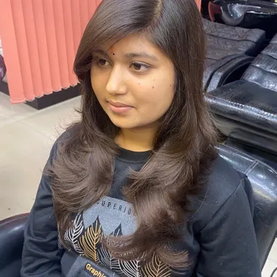 A beautiful feather-cut with side-swept bangs. This style is perfect for adding softness and volume around the face, creating a flattering and modern look.
