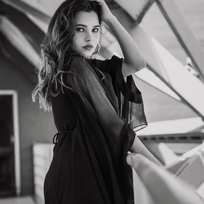 This black and white fashion portrait emphasizes the model's intense gaze and the texture of her dress, creating a dramatic and timeless look.