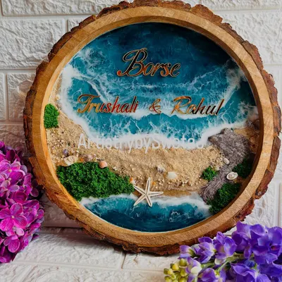 Bringing the beach to your doorstep. This personalized ocean-themed nameplate is set in a natural wood slice and features real sand, seashells, and beautiful resin waves.