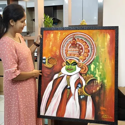 Holding up the finished Kathakali piece. You can see the size and how the dark frame makes the bright colors of the artwork pop.