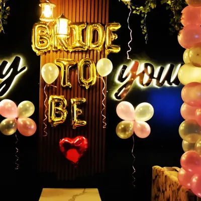 A cozy and intimate "Bride to Be" setup in a restaurant. The gold foil letters and neon signs create a warm and celebratory glow for the future bride.