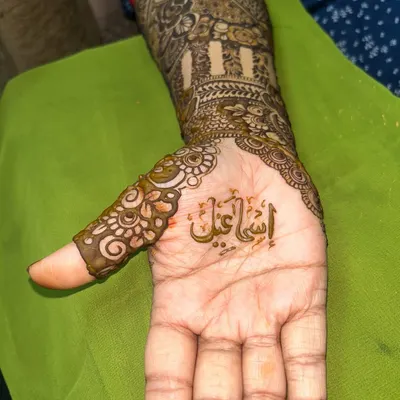 A close-up of a name written in beautiful Arabic calligraphy, nestled in the palm of a bridal design.
