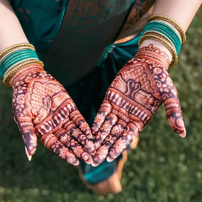 A close-up of the bride's beautiful mehendi, featuring intricate peacock and floral designs. We love capturing this traditional art.