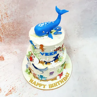 A side view of our two-tier Whale Cake, showcasing a variety of sea creatures like crabs, stingrays, and fish swimming around the tiers.