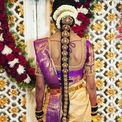 A stunning shot of a South Indian bride's traditional hairstyle, featuring an intricate hair braid ornament (Jadai Billai) and fresh flowers.