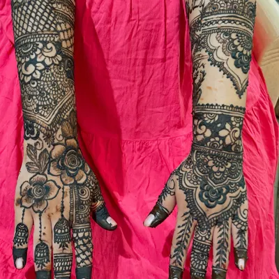 A close-up of the bride's hands, where you can see the initial 'R' beautifully integrated into the traditional design on her right wrist. It's a subtle yet meaningful way to personalize your bridal henna.