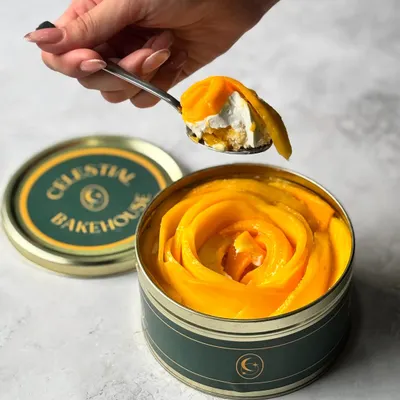 A perfect spoonful of our Mango Tres Leches. You can see the layers of light sponge, creamy filling, and fresh mango in every bite.