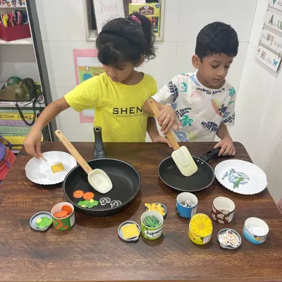 We firmly believe that children learn best when they are playing. This photo captures a moment from our "Young Chefs" theme, where students use toy food and pans to learn new vocabulary, practice sequencing, and develop conversational skills.