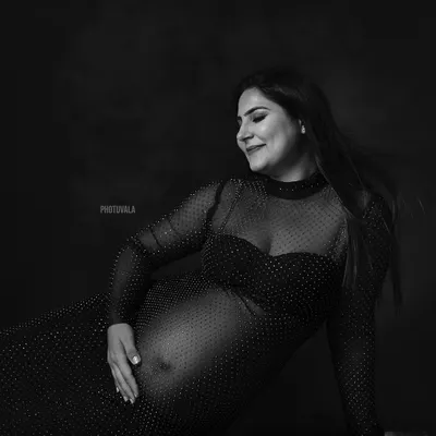 A classic black and white portrait celebrating the beautiful curves of pregnancy. This shot, inspired by Bollywood elegance, focuses on the quiet confidence of the mother-to-be.