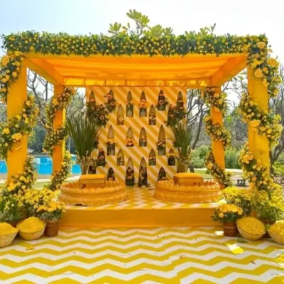 A classic Haldi mandap drenched in yellow. The setup features a beautiful floral frame, traditional seating, and a chevron-patterned floor, all coming together for a picture-perfect ceremony.