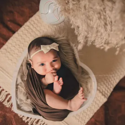 I love capturing those moments when a newborn is awake and curious. This little one, nestled in a heart-shaped bowl with a simple wrap, looks right at the camera, showing off their beautiful, expressive eyes.