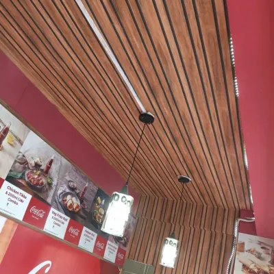 A closer look at the fluted paneling on the ceiling of a cafe. This application draws the eye upward and adds texture and warmth to the entire room, complementing the wall decor.