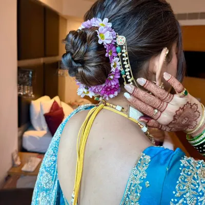 A detailed shot of a classic bridal bun, adorned with a mix of purple and white flowers and a traditional hair accessory. This style is perfect for securing a heavy dupatta.