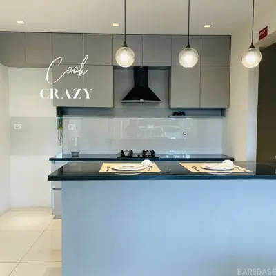 This kitchen is all about clean, modern elegance. We paired two-tone gray and white cabinets with a sleek black chimney and an island that doubles as a breakfast counter, illuminated by stylish pendant lights.