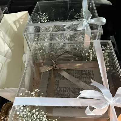 We believe every bride deserves a welcome wrapped in love. Our elegant trousseau packaging features clear acrylic boxes adorned with delicate baby's breath and satin ribbons to protect and display your precious garments.