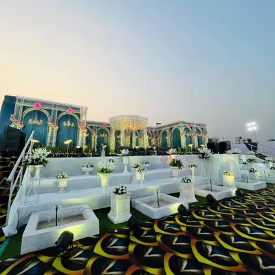 This is the kind of grandeur I love to create. For this royal reception, I designed a massive, multi-level stage with teal and white palace-style arches, a central mandap, and intricate water features to give the couple a truly majestic experience.