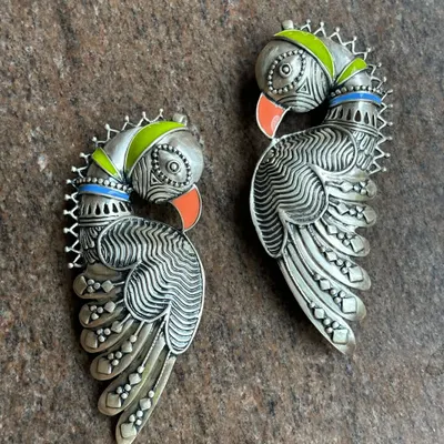 An exclusive pure silver peacock ear cuff. This is not your average earring; it's a statement piece of art that curves gracefully along the ear, with colourful enamel accents on the beak and crest.