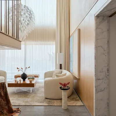 This double-height living room in the NG Penthouse is all about volume and light. The design uses a neutral color scheme, sheer curtains, and reflective surfaces to maximize the sense of openness, making spaciousness the ultimate luxury.