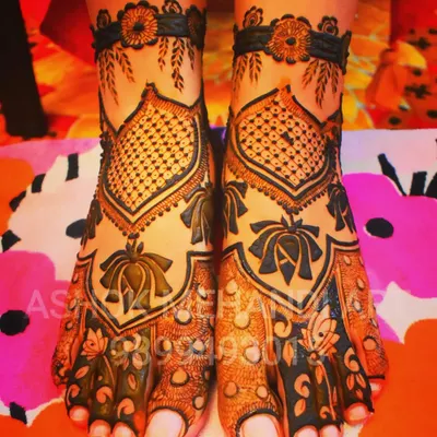 An elegant feet mehndi design featuring lotus motifs and intricate net patterns (jaal). The design creates a beautiful V-shape that elongates the feet.