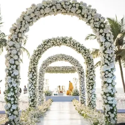 I designed this breathtaking wedding aisle with a series of grand arches made entirely of white flowers. This created a stunning walkway leading to the beachside mandap, making the bride's entrance truly unforgettable.