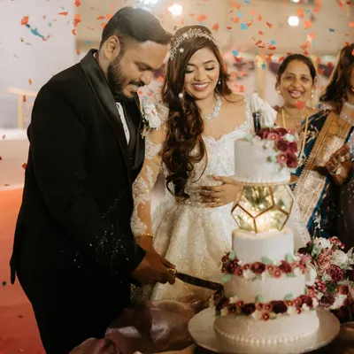 A beautiful moment from a Christian wedding cake-cutting. The bride's makeup is elegant and timeless, mirroring her inner joy.